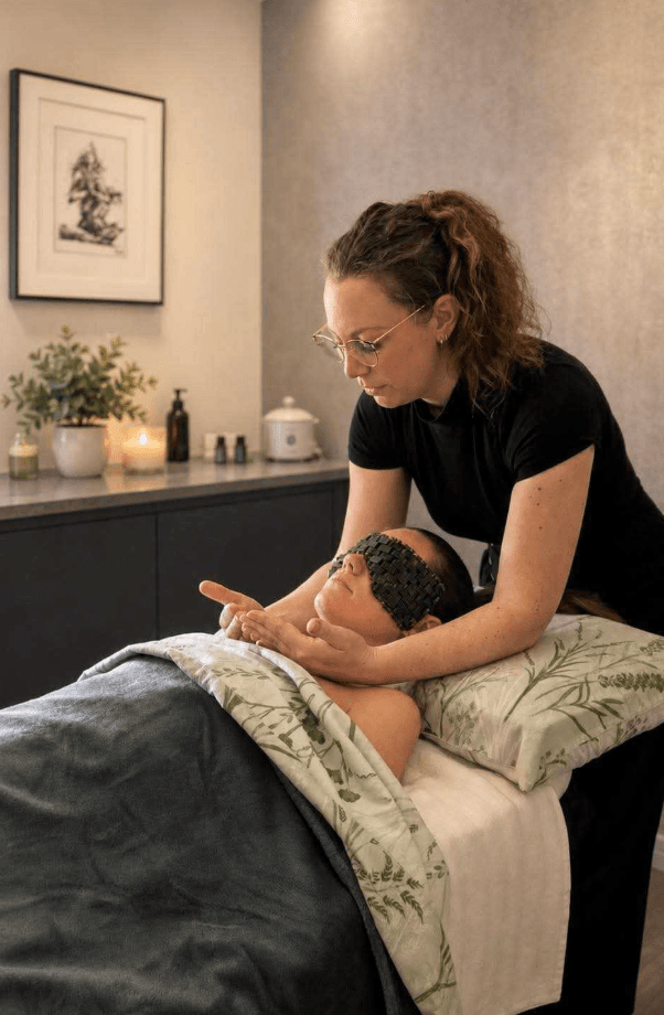 Kim Homewood performing a gentle facial massage at Nurture Body Therapy — client resting with a calming green eye mask, illustrating the postnatal Mothers Massage experience